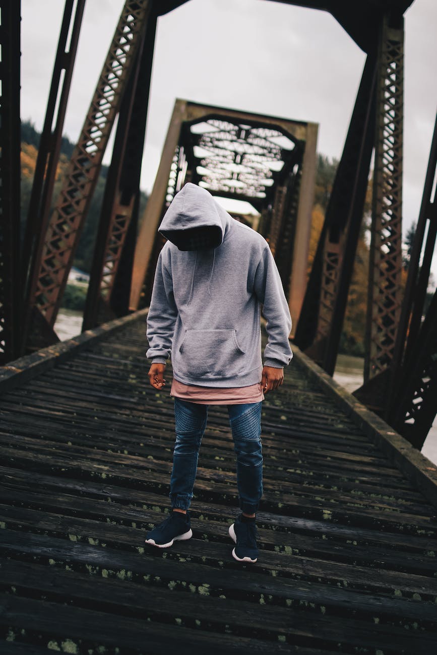 man in gray pull over hoodie standing on train rail